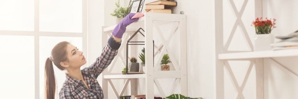 Woman dusts surfaces in her home to keep it free of possibly hazardous dust particles. 